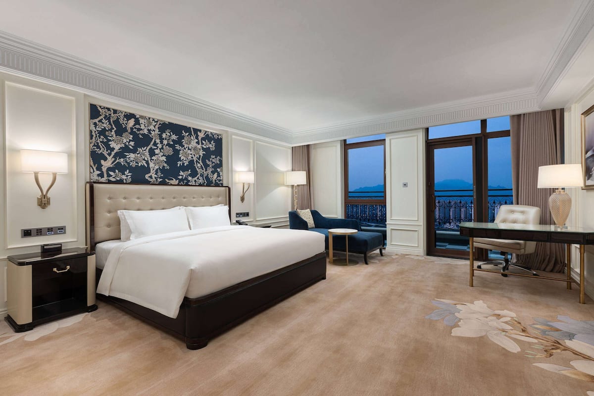 Une chambre d’hôtel avec un grand lit, un bureau, une chaise et une vue sur la mer.