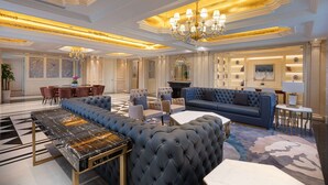 Un salon luxueux avec un grand canapé bleu, une table basse en marbre et un lustre.