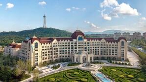 Un grande hotel con un cortile centrale, una torre sullo sfondo e un paesaggio montuoso.
