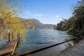 A wooden dock extending into a calm lake with a mountain in the background. - Maison Sur l Eau in Paradiso Lugano (Paradiso)