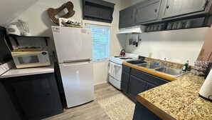 Una cocina compacta equipada con refrigerador, microondas, estufa y lavabo.