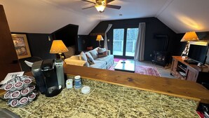 Un salón acogedor con ventilador de techo, chimenea y un ventanal con cortinas.
