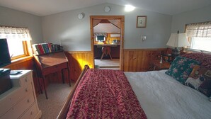 Un dormitorio con cama, escritorio, silla y televisor.