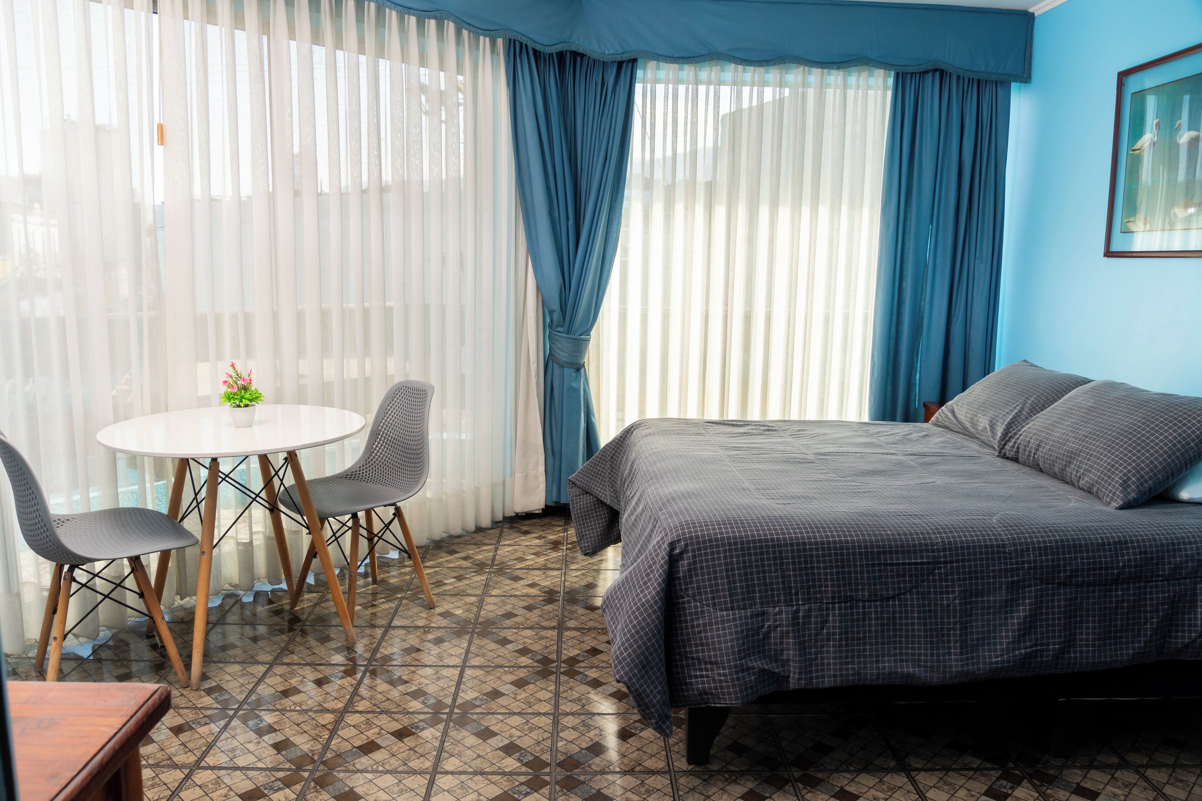 A bedroom with a bed, a round table with chairs, and a potted plant.