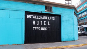 A turquoise building with a black garage door labeled "ESTACIONAMI ENTO HOTEL TERRANOR T". - HOTEL TERRANORT (Iquique)