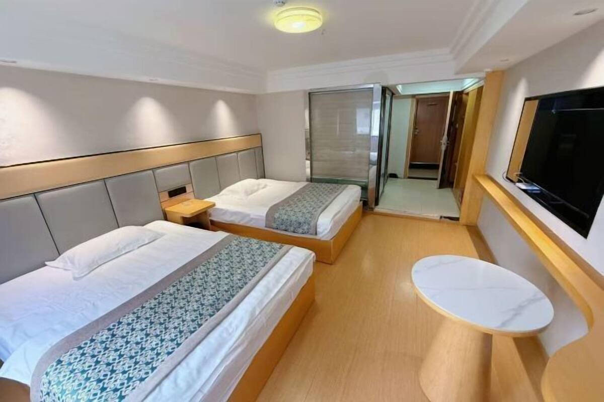 Ein Hotelzimmer mit zwei Betten, einem kleinen Tisch und einem Fernseher.