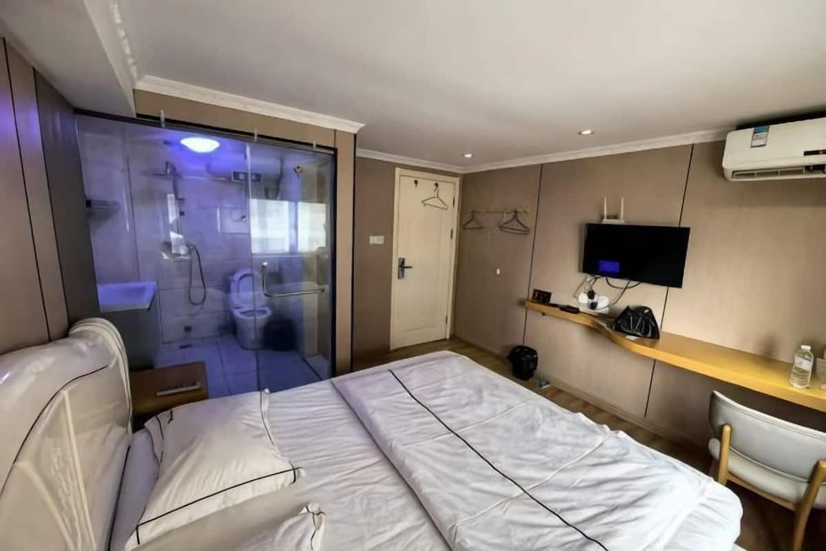 Ein Hotelzimmer mit Bett, Schreibtisch, Fernseher, Duschbereich und Kleiderschrank.
