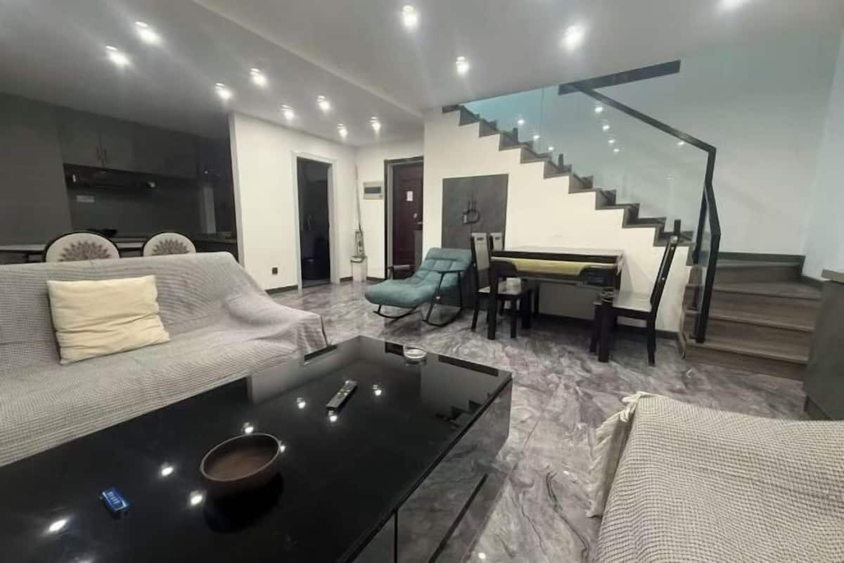 Ein modernes Wohnzimmer mit einer Couch, einem Couchtisch und einer Treppe.