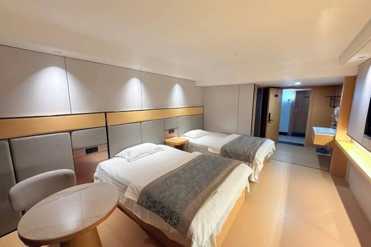 Ein Hotelzimmer mit zwei Betten, einem kleinen Tisch und einem Spiegel.