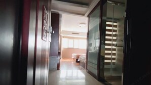 A hallway leading to a bedroom with a bed and a window. - Kuaile Holiday Hotel (Lianyungang)