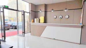 A reception area with a glass door, a reception desk, and a wall-mounted clock. - Kuaile Holiday Hotel (Lianyungang)