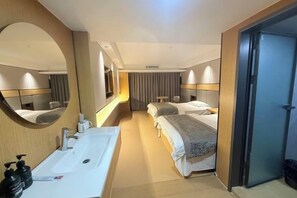 Une chambre d’hôtel avec un grand miroir, un lavabo, deux lits et une porte.