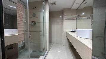 Un baño moderno con cabina de ducha de vidrio, un lavamanos blanco y un espejo.