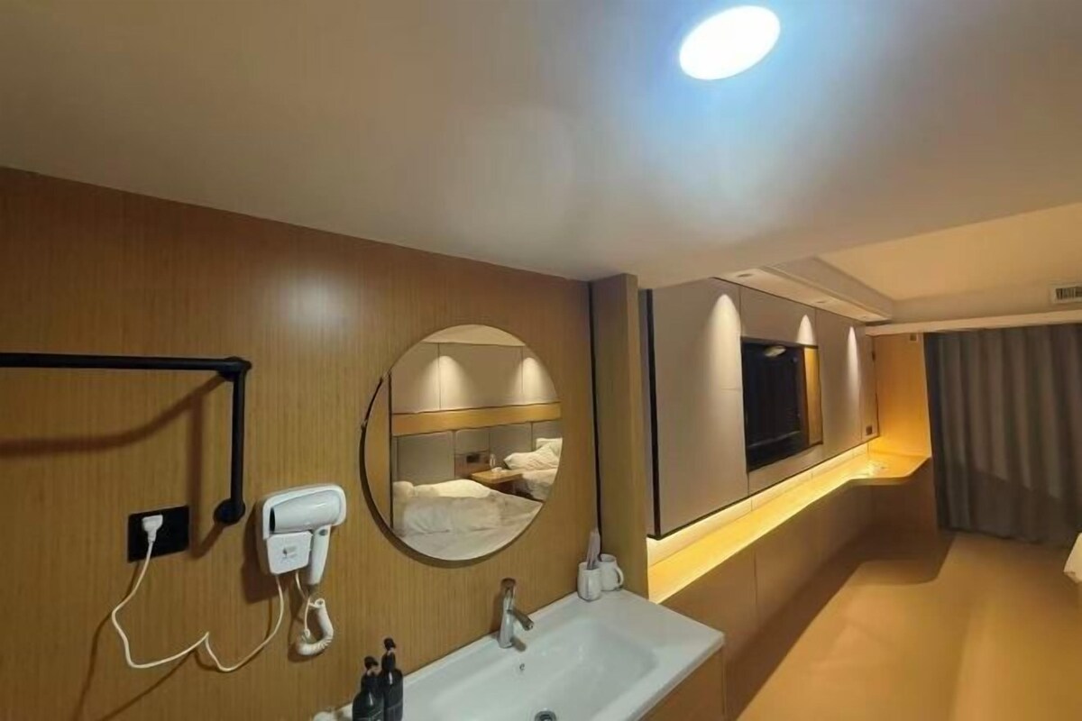 Une chambre d’hôtel avec un lit, une salle de bain comprenant un lavabo, un miroir et une fenêtre.