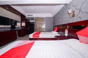 Ein Hotelzimmer mit zwei Betten, einem Fernseher, einer Minibar und einer Wanddekoration.