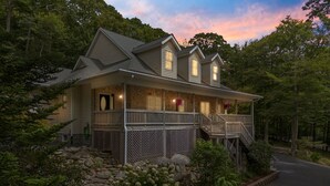 A two-story house with a stone facade, a balcony, and a porch.