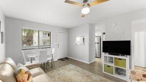 Una sala de estar moderna con un sofá, un televisor y un ventilador de techo.