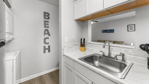 Una cocina moderna con armarios blancos, encimera de mármol y pileta de acero inoxidable.