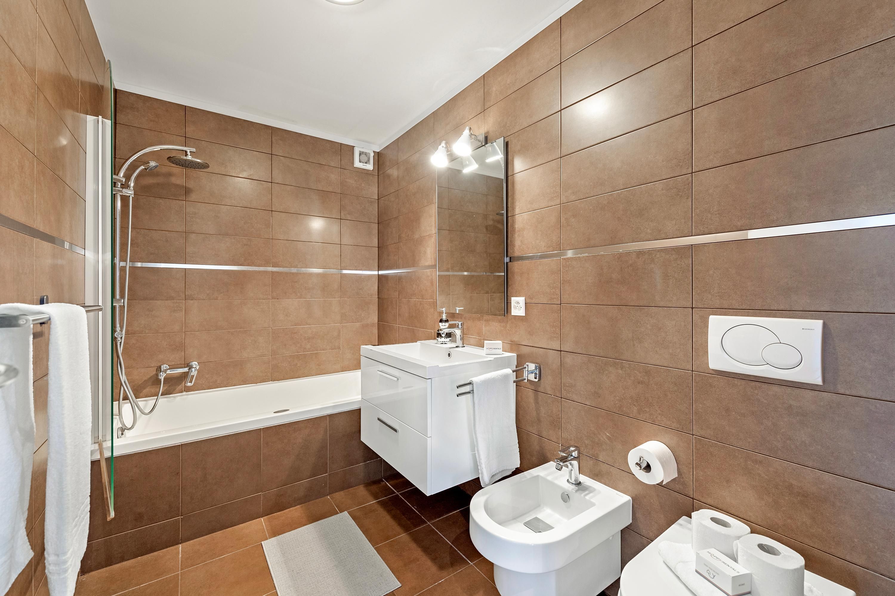 A modern bathroom with a bathtub, a shower, a bidet, and a toilet.