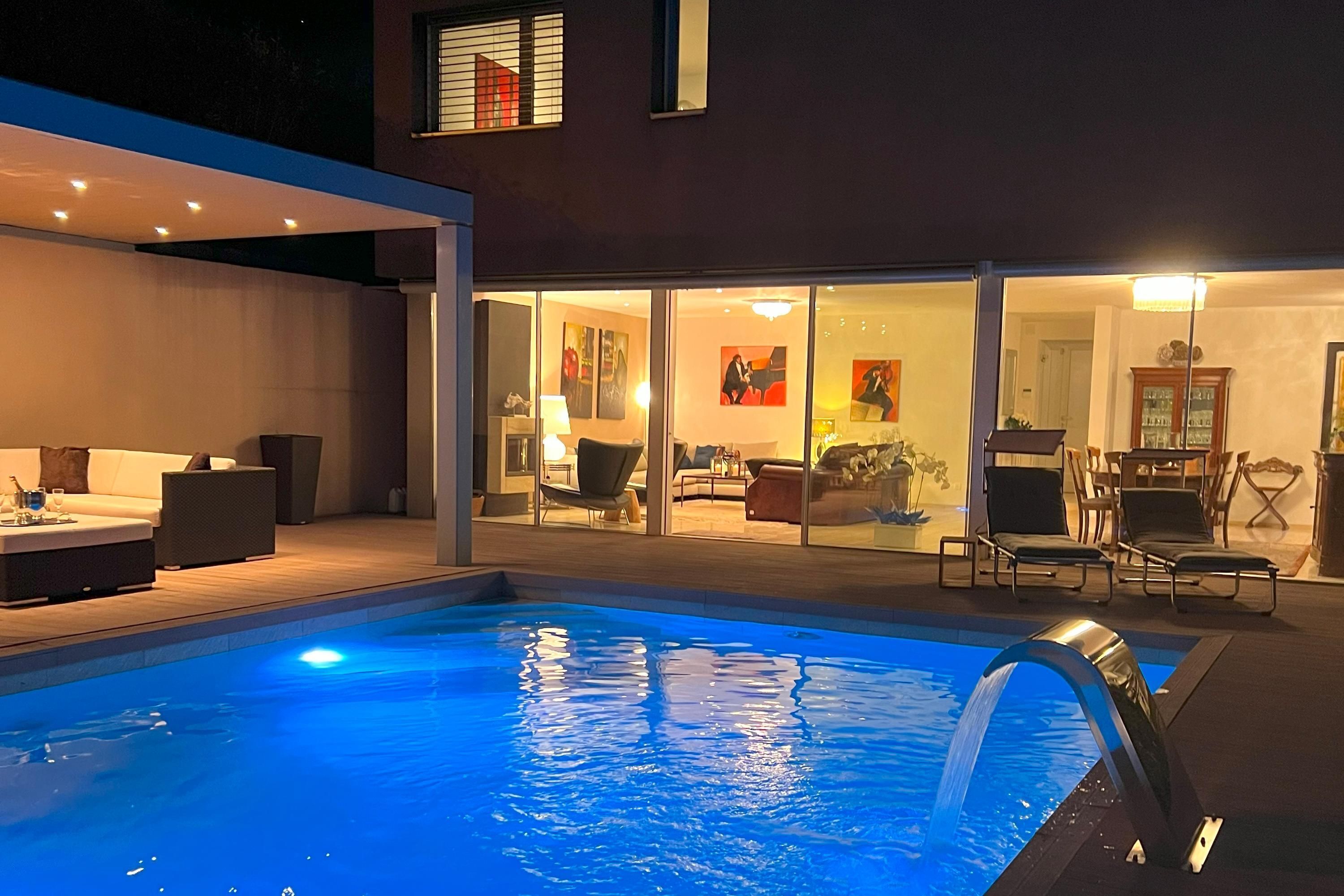 An outdoor swimming pool with a modern house in the background.