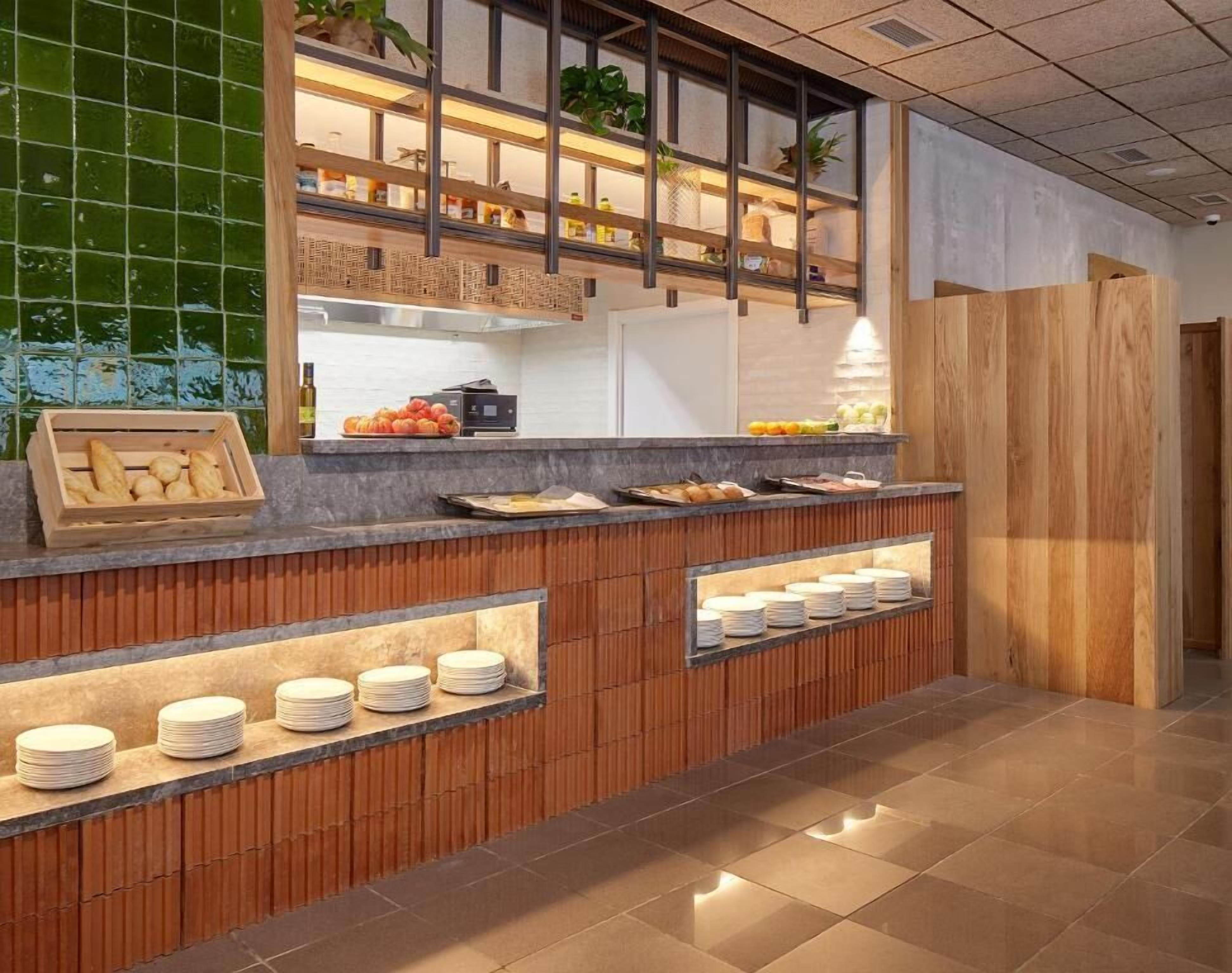 Una recepción moderna con un mostrador de madera, vitrinas de vidrio y una pared de azulejos verdes.