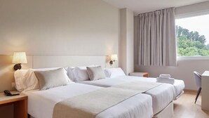A hotel room with two beds, a desk, and a chair. - Hotel Sukha (Eskoriatza)