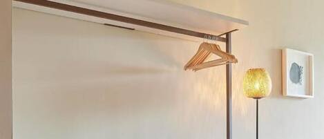 Una habitación minimalista con una consola blanca, una lámpara de pie y un cuadro en la pared.