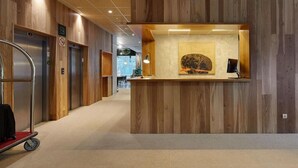 A reception area with wooden paneling, a reception desk, and two elevators. - Hotel Sukha (Eskoriatza)