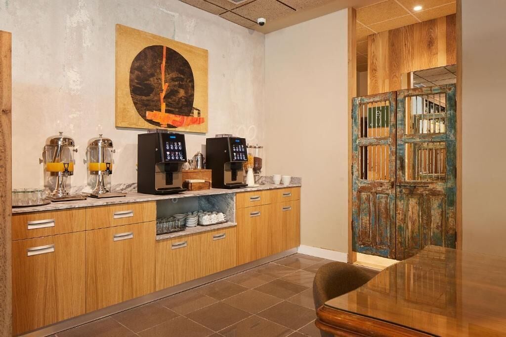 A modern kitchen with wooden cabinets, a marble countertop, and a coffee machine.