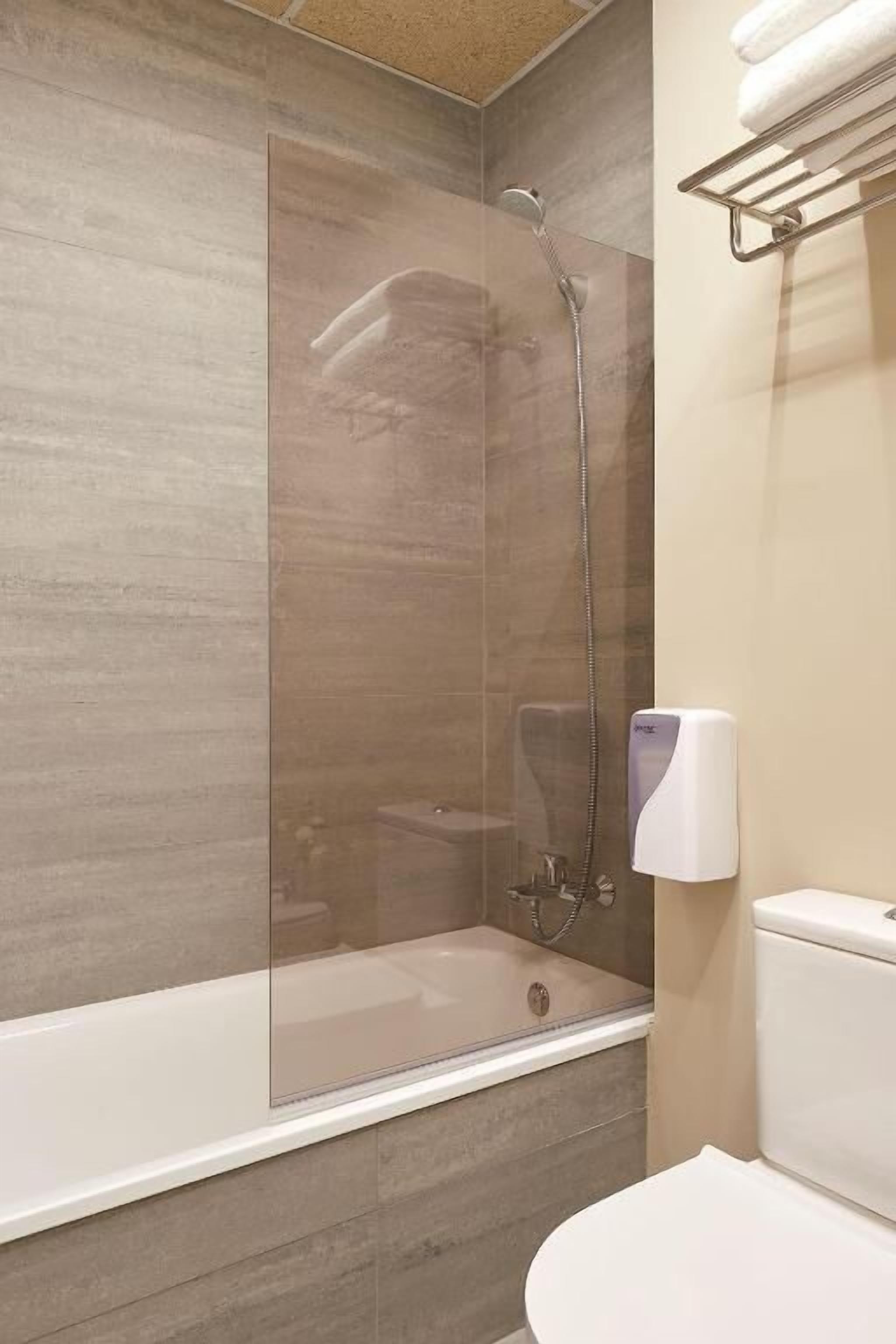 A modern bathroom with a glass-enclosed shower, a toilet, and a towel rack.