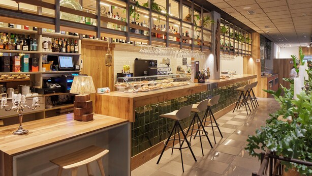 A bar area with a counter, stools, and shelves stocked with bottles. - Hotel Sukha (Eskoriatza)