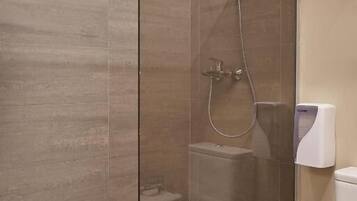 A modern bathroom with a glass-enclosed shower, a toilet, and a towel rack.