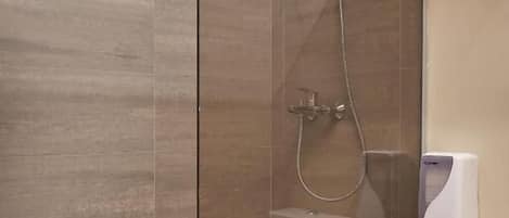 A modern bathroom with a glass-enclosed shower, a toilet, and a towel rack.