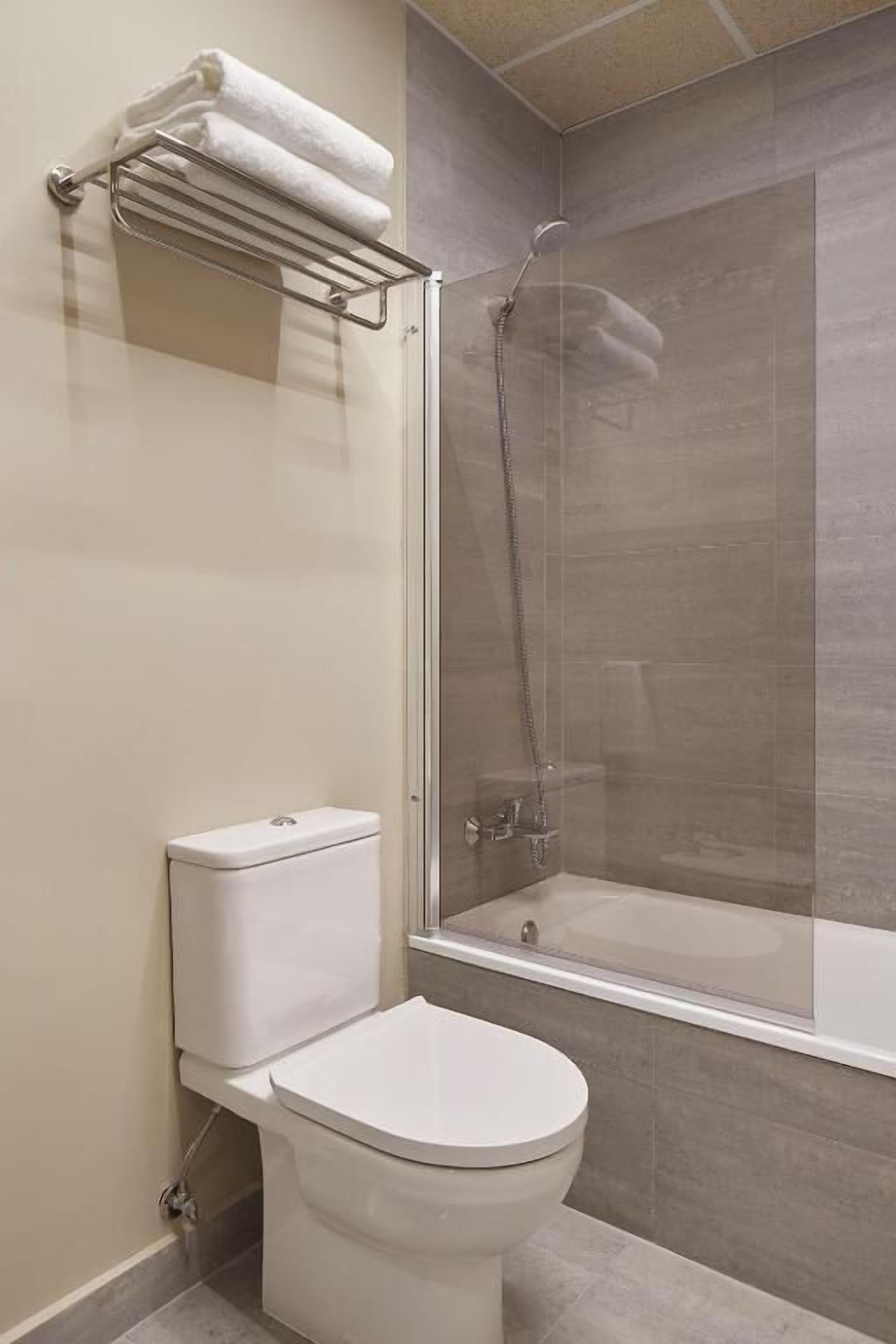 Een moderne badkamer met een toilet, een douchecabine en een handdoekrek.