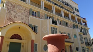 A multi-story building with balconies, a large terracotta pot, and a door with a decorative arch. - 2 ROOM APARTMENT NEAR THE SEA AND PINES OF JUAN-LES-PINS (Antibes)