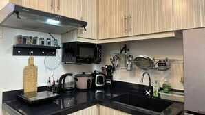 Una cocina moderna con armarios de madera, encimera negra, microondas, cafetera y fregadero.