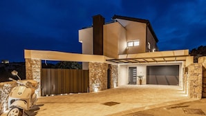 A modern two-story house with a stone facade, a garage, and a scooter parked in front. - Villa Betelgeuse Supernova (Novi Vinodolski)