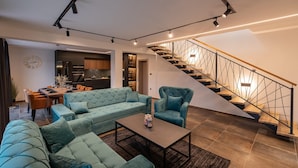 A modern living room with a sectional sofa, a coffee table, and a staircase with a metal railing. - Villa Betelgeuse Supernova (Novi Vinodolski)