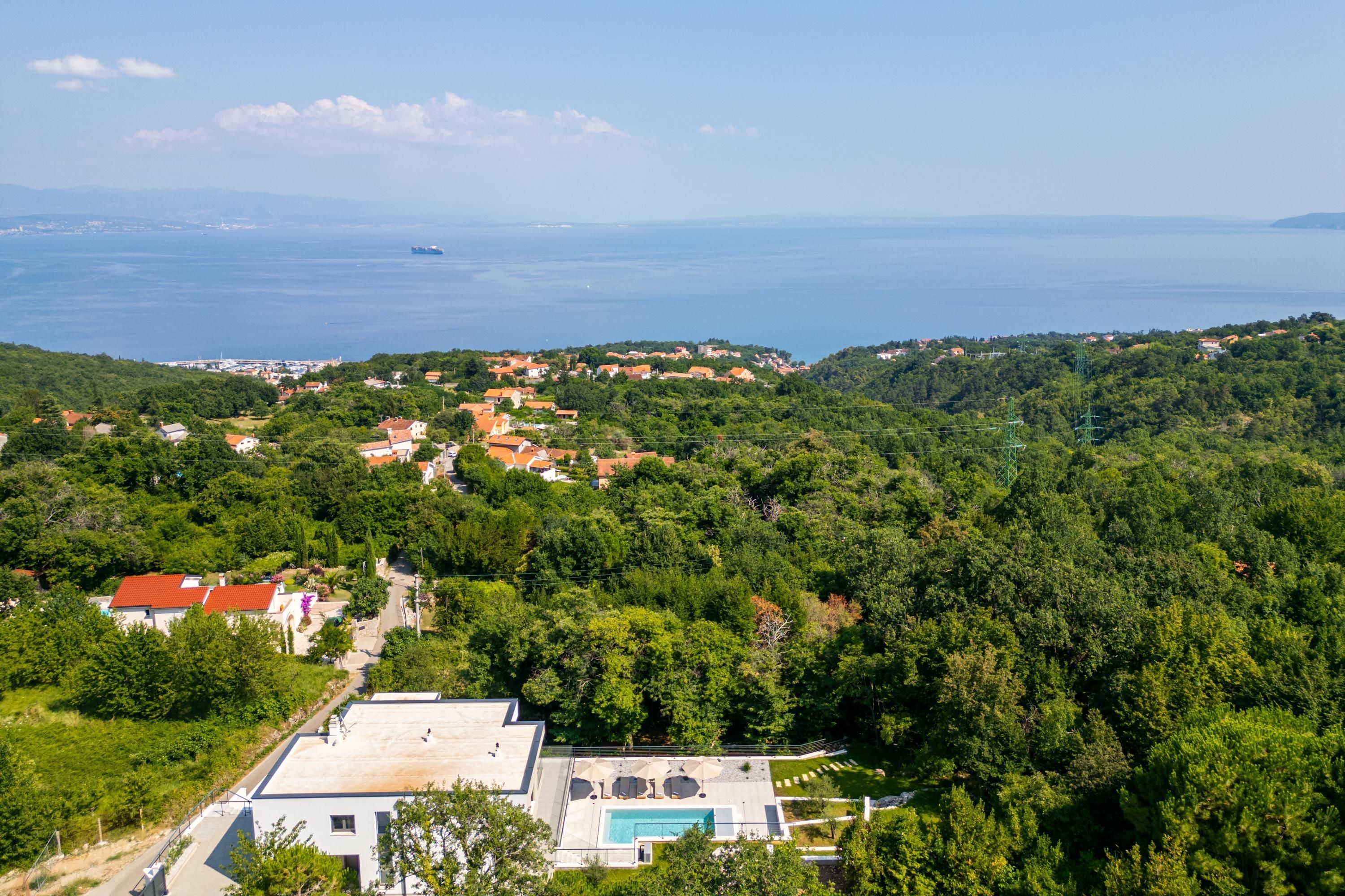 A coastal village with houses, a swimming pool, and a view of the sea.