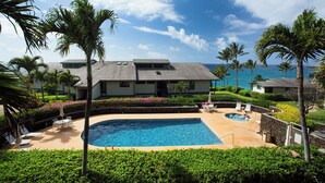 Un resort con piscina, palmeras y vista al océano.