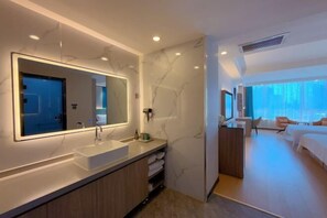 A modern hotel room with a large mirror, a built-in sink, a wooden vanity, a bed, and a view of the city. - Qingzhu·Youyang Hotel (Guang'an Street Museum Metro Station) (Shijiazhuang)