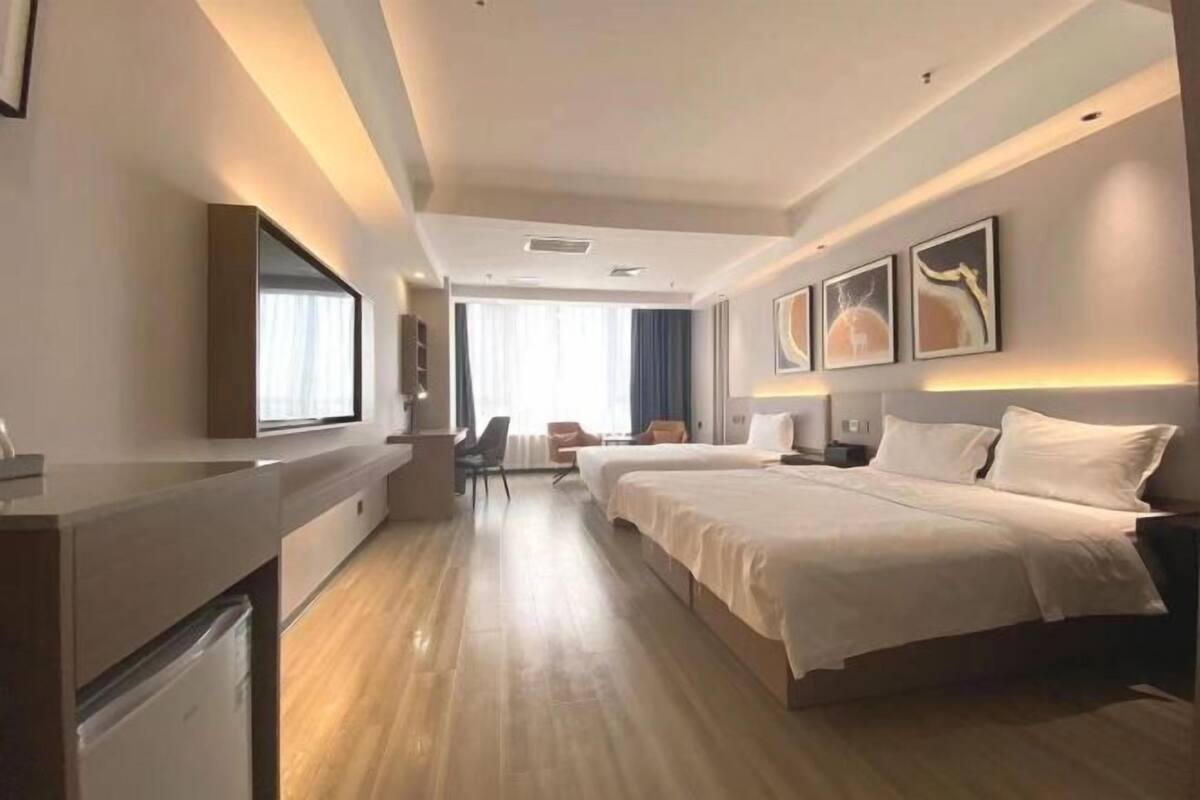 A hotel room with a bed, bedside tables, a desk, a chair, and a window.