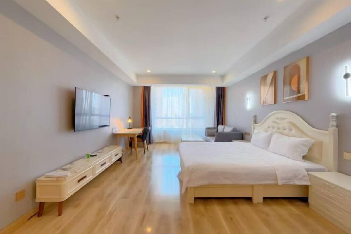 A modern hotel room with a large bed, a desk, and a television.