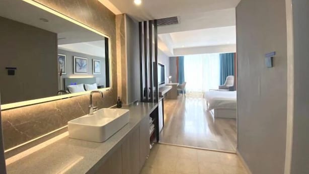 Ein modernes Hotelbad mit großem Spiegel, Waschbecken und Duschbereich.