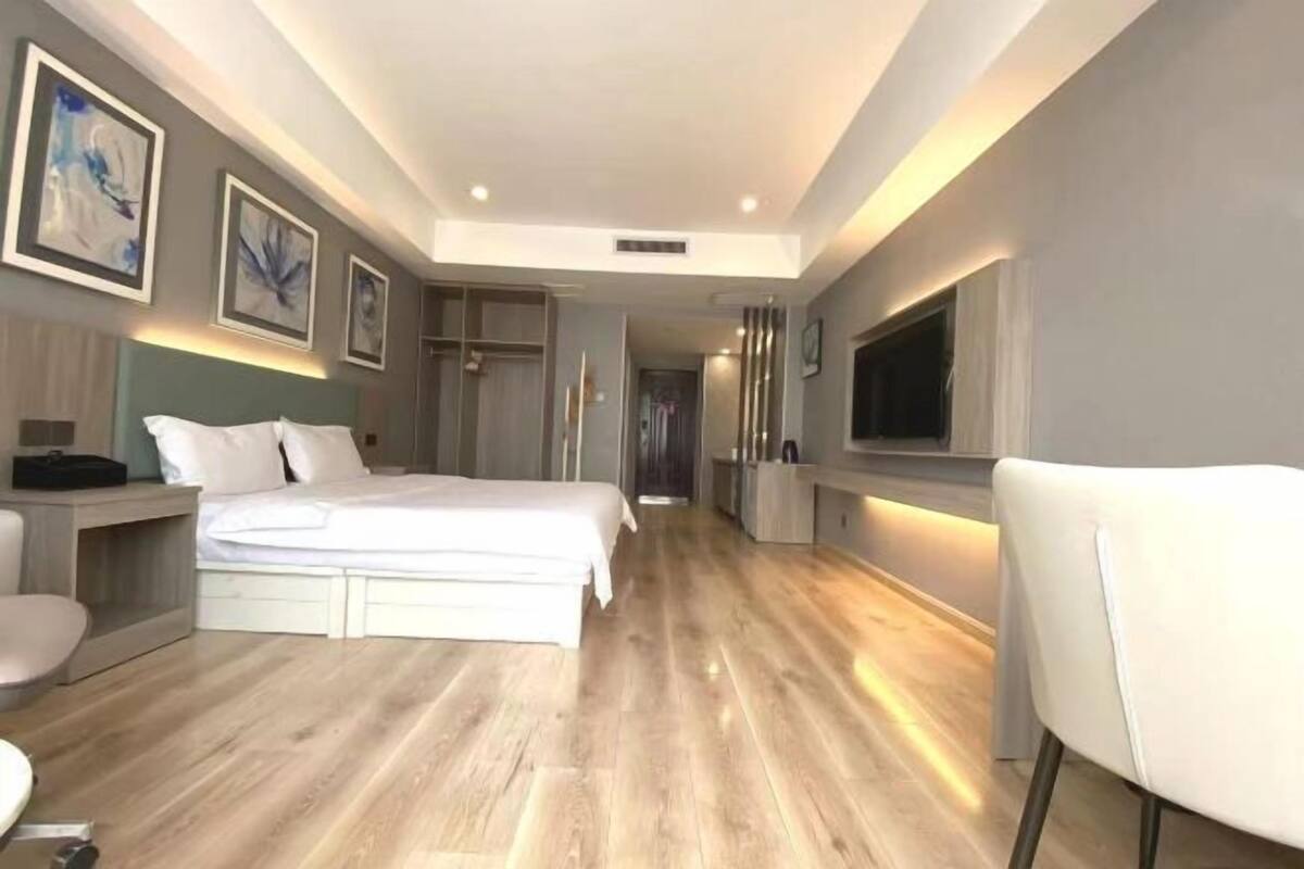 A modern hotel room with a large bed, a desk, a chair, and artwork on the walls.