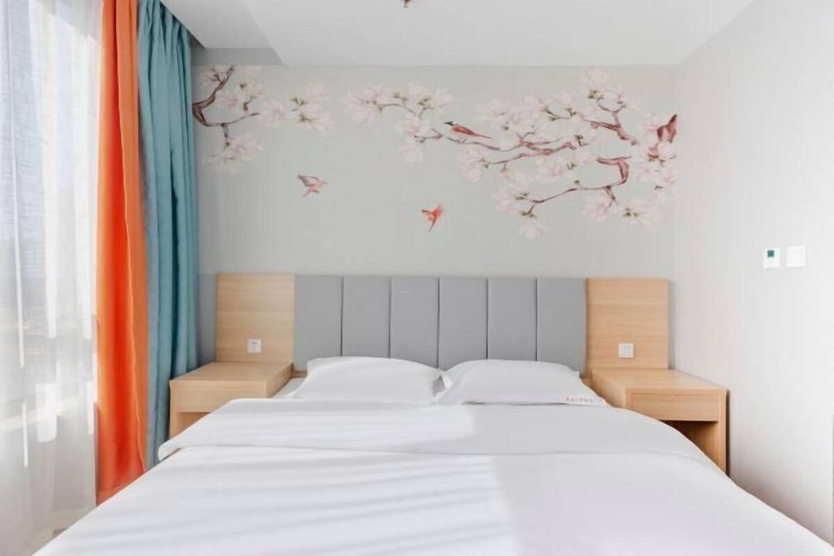 A hotel room with a bed, two nightstands, and a wall with floral decals.