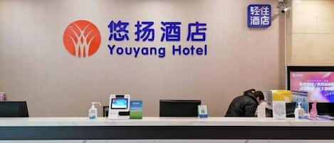 A reception desk at Youyang Hotel with a digital screen, a water dispenser, and a television.