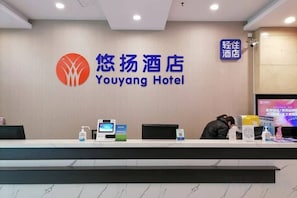 Mostrador de recepción en el Hotel Youyang con una pantalla digital, un dispensador de agua y un televisor.