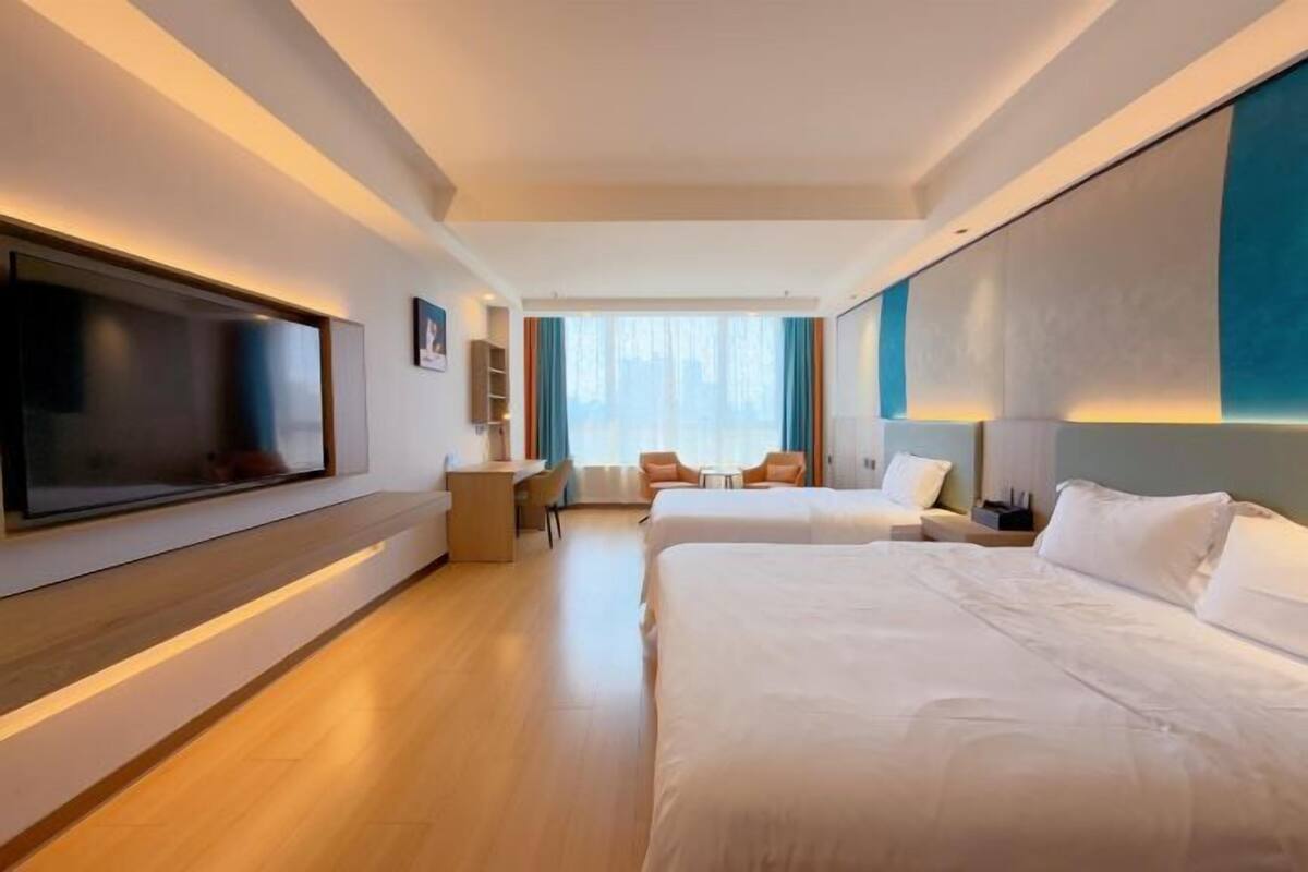 A hotel room with two beds, a TV, a desk, and a seating area with chairs.