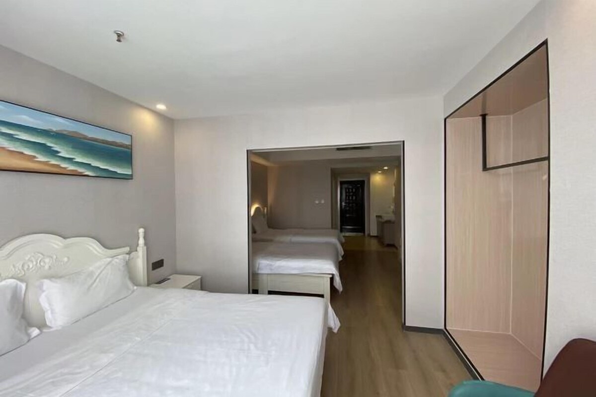 A hotel room with a bed, bedside tables, and a painting of a beach scene.